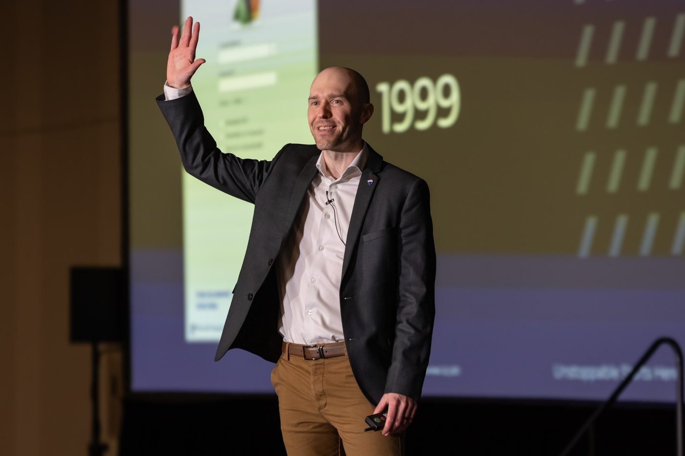 Wade Paterson waving to the audience while presenting on stage